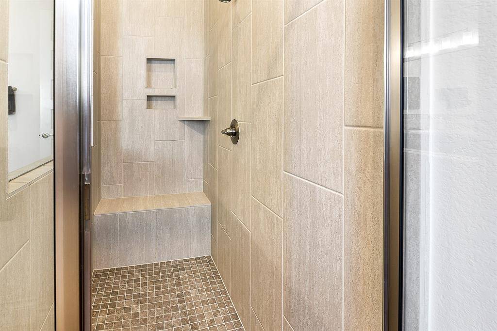 This luxurious tiled shower offers ample space, complete with built-in bench seating and convenient soap and shampoo cubbies.