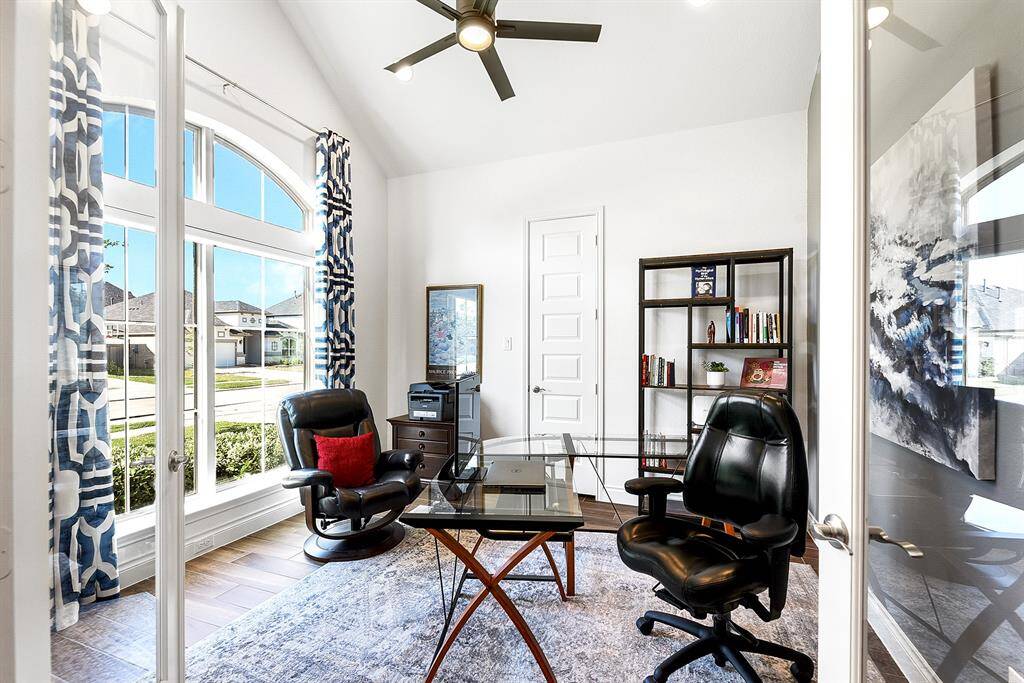 As you enter through the front door, you’ll find glass French doors to the left, leading into a private home office. This versatile space features a wall of windows with views of the front yard, high ceilings, recessed lighting, and a ceiling fan for added comfort. A closet offers additional storage, making this room functional for work or flexible living space.