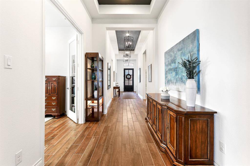 Stepping further back, French doors to the left lead to a game room or flex space, while across the hall on the right, you'll find a guest hallway that leads to two bedrooms and a guest bathroom.