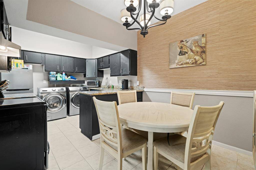 This angle shows how the kitchen and dining area come together to create a seamless and functional space, allowing for easy movement and interaction throughout. A striking light fixture enhances the atmosphere, making the area ideal for both daily routines and lively gatherings.