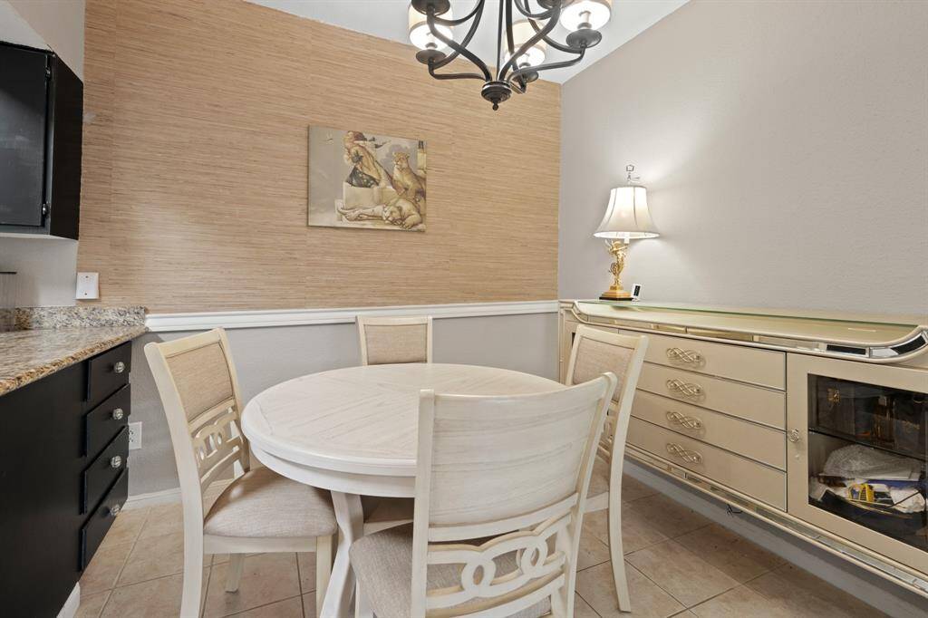 The dining room’s accent wall features textured wallpaper that adds warmth and depth, creating a dynamic visual element in the space. Its natural, woven pattern enhances the overall ambiance, making the room feel inviting and refined.