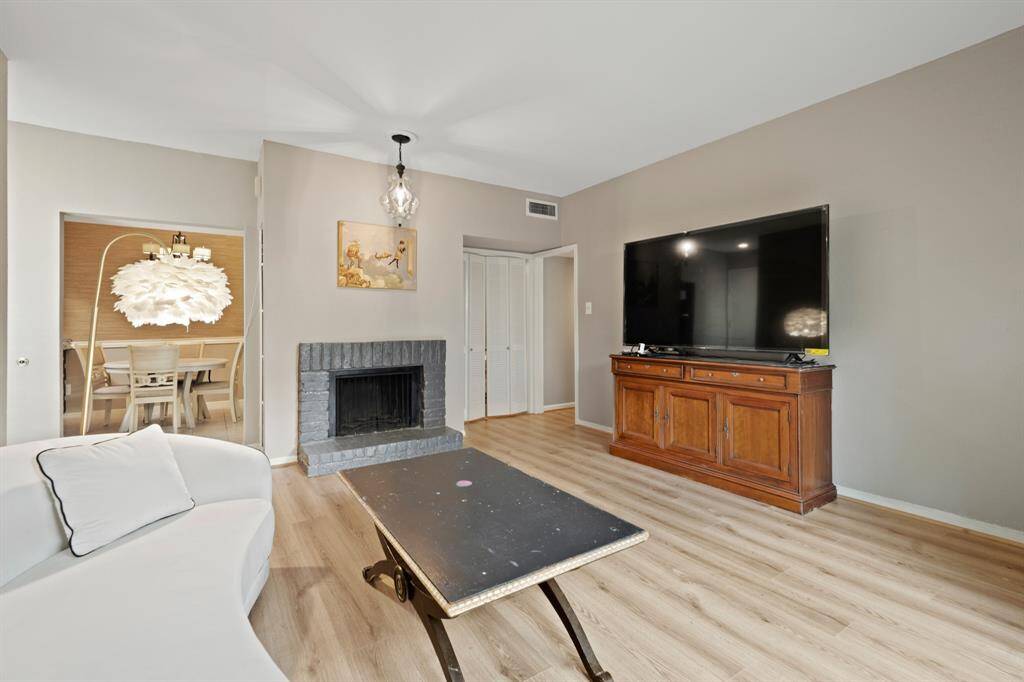 This angle highlights the smooth transition between the living room and kitchen, creating an open, spacious layout that enhances both practicality and comfort. Double doors to the right provide access to a bonus room, while the living area features a simple yet inviting fireplace that complements the overall design.