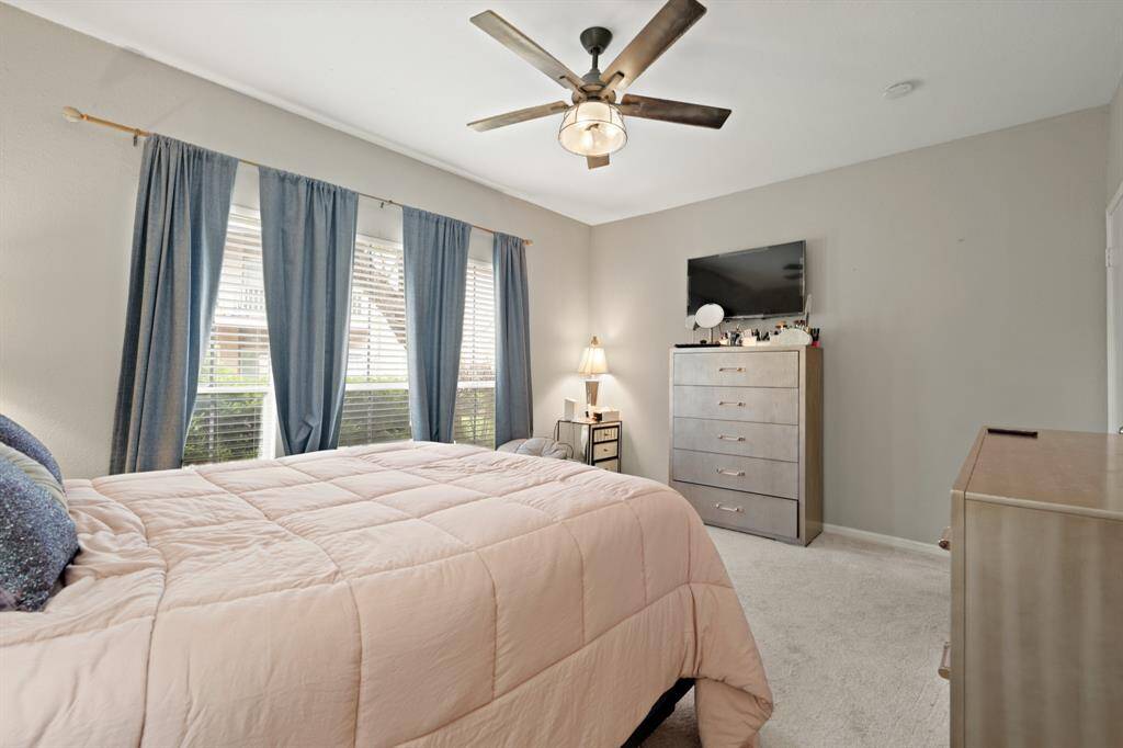 The expansive windows in the primary bedroom fill the space with natural light, creating a bright and airy atmosphere. Their generous size enhances the connection to the outdoors, offering a peaceful view of the surrounding greenery.