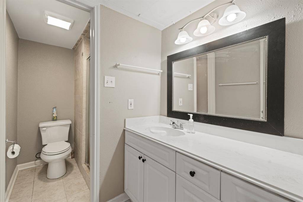 The primary bathroom features a spacious stand-up shower enclosed by a glass door and a partial wall, offering both openness and privacy. Its sleek design enhances both style and functionality, making it a key highlight of the space.