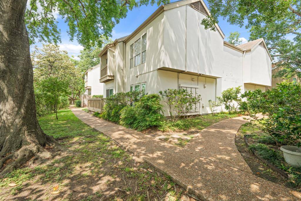 A curved pathway, bordered by bushes and trees, leads to multiple entrances, offering a sense of privacy and accessibility. The thoughtful landscaping enhances the serene and inviting atmosphere of the area.