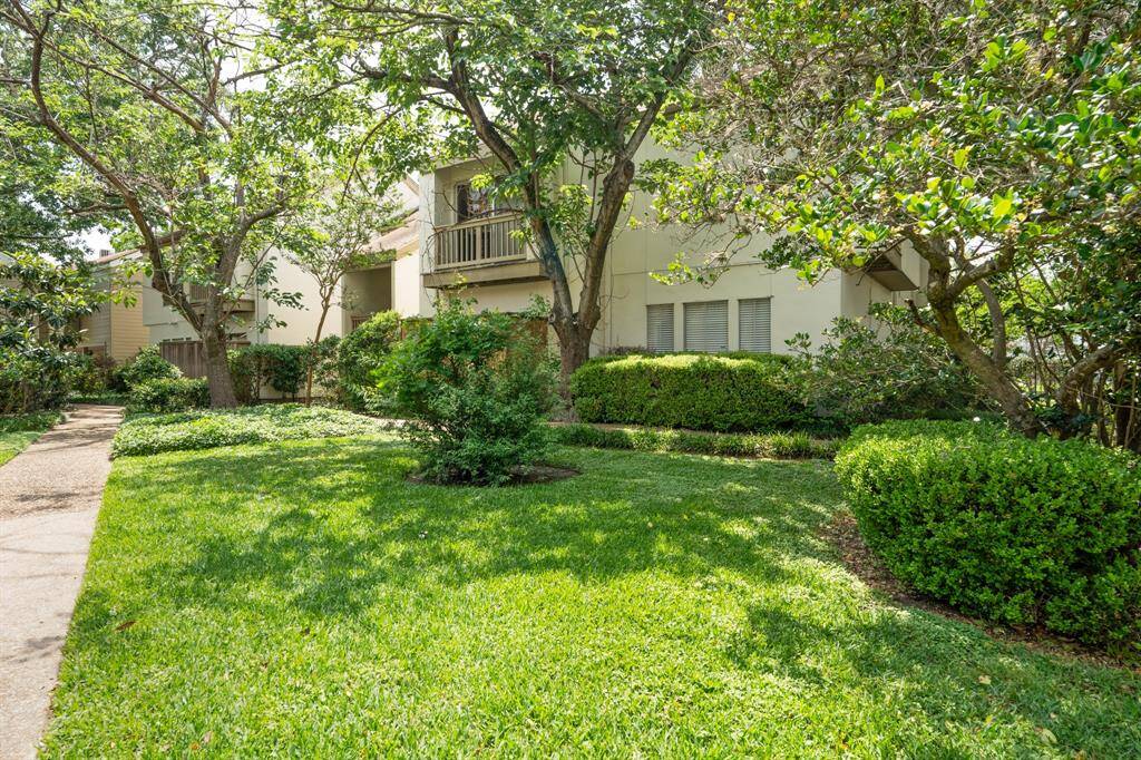 Peaceful residential area around the unit. featuring a pathway that winds through a lush green lawn surrounded by trees and bushes