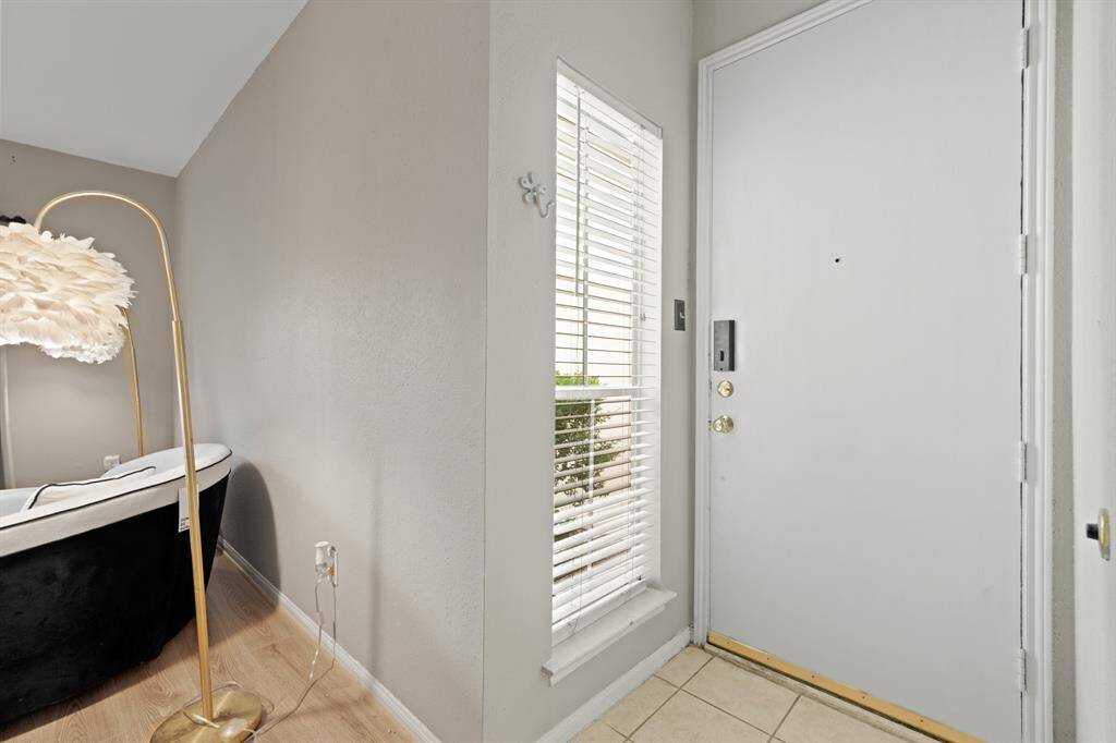 The entryway feels open and welcoming, with natural light streaming through the window next to the door, offering a refreshing glimpse of greenery outside. The simple and functional layout enhances the bright atmosphere, creating an inviting transition into the home.