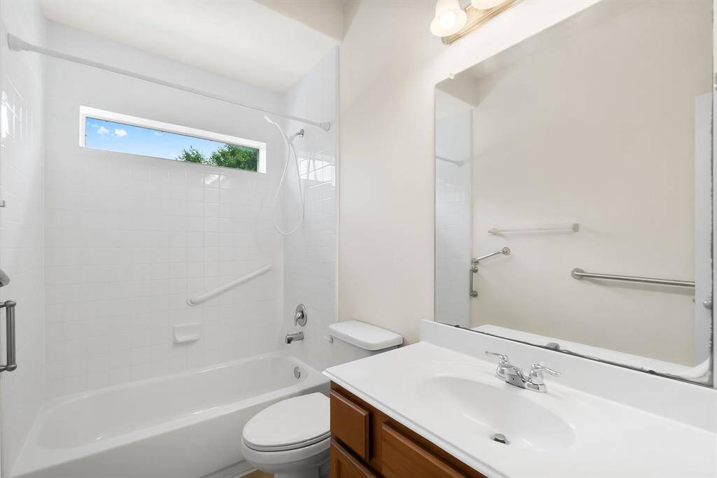 Bright and clean bathroom featuring a shower-tub combo with a window for natural light, modern fixtures, and a large mirror above the vanity.