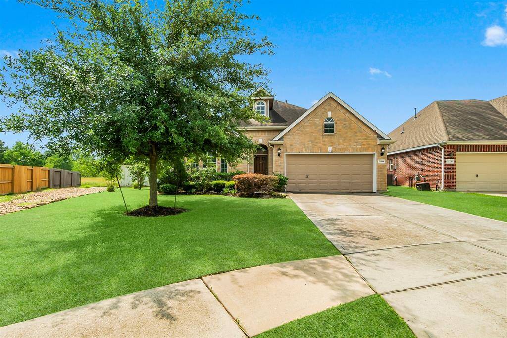 This charming brick home features a well-maintained front yard with lush green grass and a mature tree. The property includes a spacious driveway leading to a two-car garage, offering ample parking and convenience.