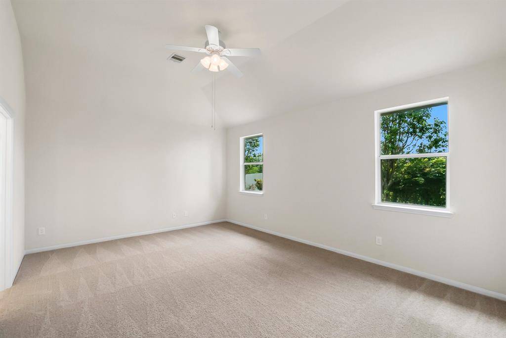 Bright dining area with tiled flooring, modern light fixture, and large windows offering lush green views. Adjacent room is carpeted, adding warmth and comfort.