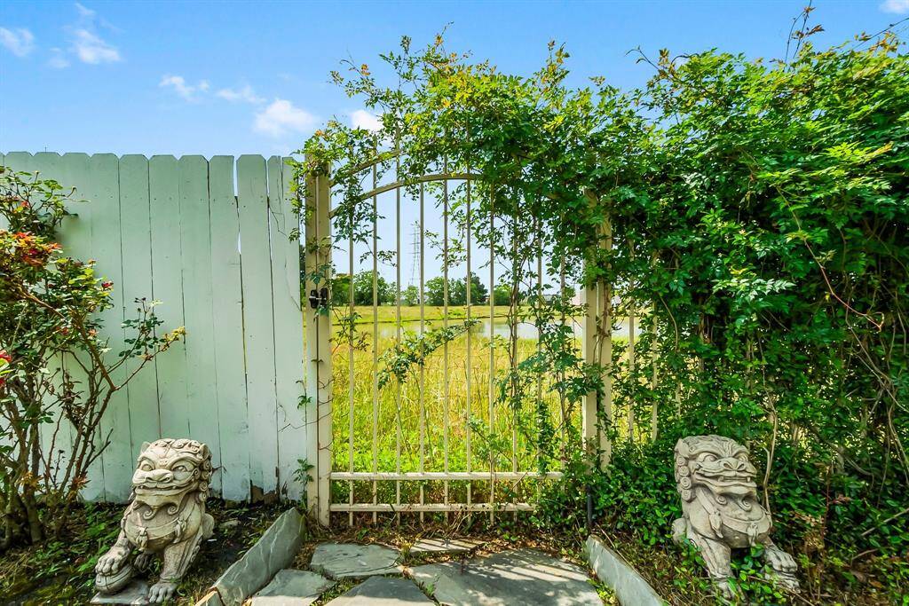 Cozy backyard patio features a covered seating area with ceiling fan, stone walkway, and privacy fence, ideal for relaxation and outdoor gatherings.