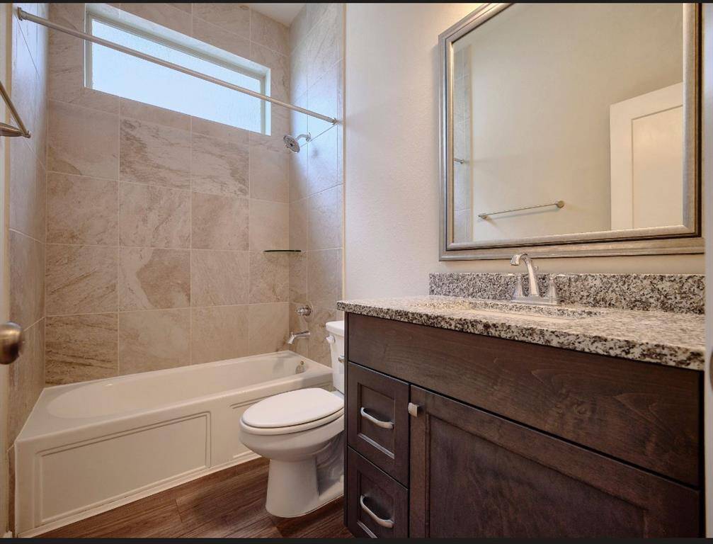 Elegant full bathroom next to the second bedroom, featuring a cultured marble vanity and a stylish framed mirror.