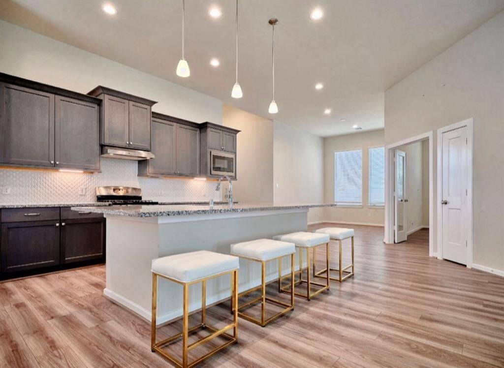 Elegant open-concept kitchen with a breakfast bar, inviting living area, recessed LED lighting, and a sleek Delta pull-down sprayer faucet.