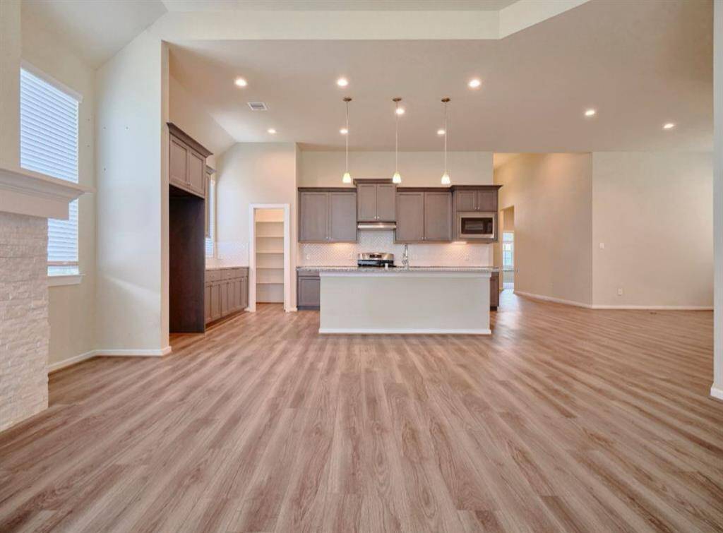 Elevate your living and kitchen spaces with stunning designer light fixtures and elegant vaulted ceilings. J-Kraft cabinetry with 42" high uppers