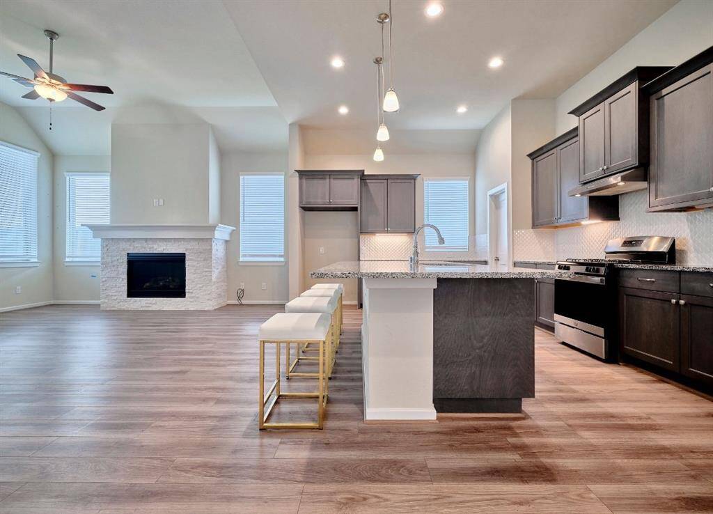 Experience modern elegance with under-counter lighting, a sleek gas stove, and a stylish tile backsplash. The countertop features an overhang for casual dining.