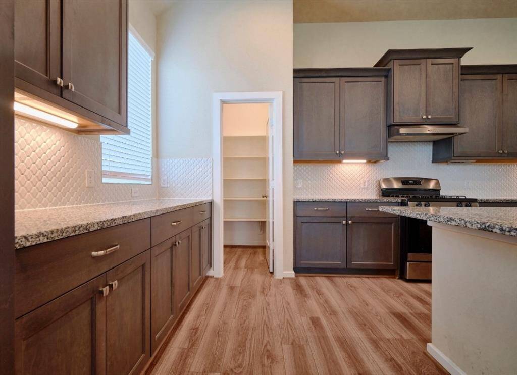 Elegant kitchen featuring granite countertops, ample storage with sleek cabinets and spacious closets, complemented by a stylish tile backsplash and modern GE black appliances.