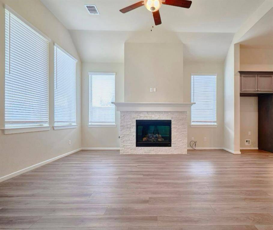 A stunning stone fireplace reaching the raised ceiling, complemented by sleek square corners, adds elegance to this space.