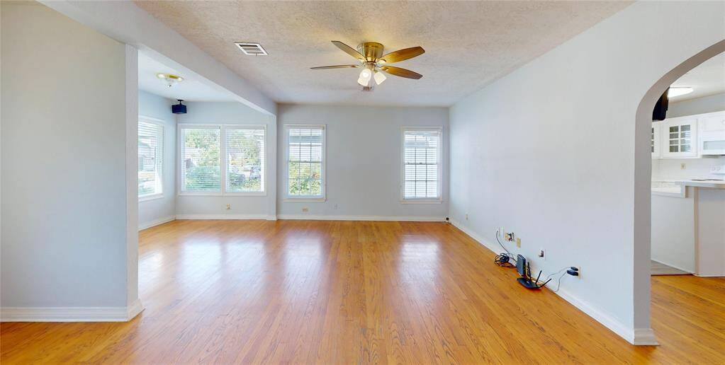 Bright and spacious living area with hardwood floors, large windows for natural light, and an open archway leading to the kitchen. Ideal for comfortable living and entertaining.