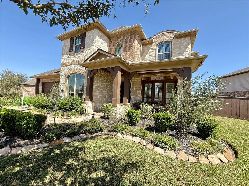 Charming two-story home with a blend of stone and brick exterior, featuring a well-maintained front garden and a welcoming porch. Ideal for family living in a serene neighborhood.