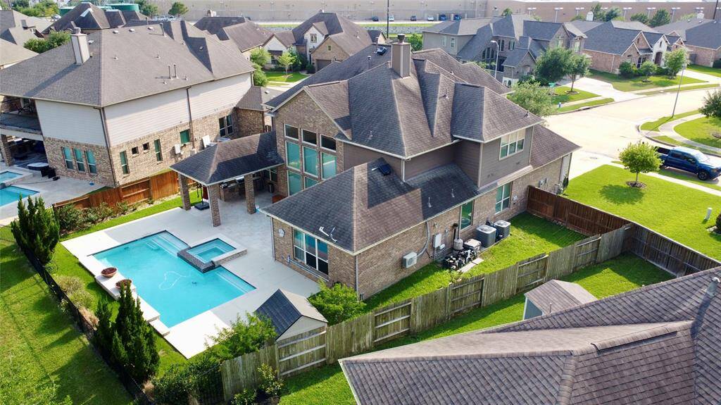 This is a spacious two-story brick house with a private backyard, featuring a pool and a covered patio. It's situated in a well-maintained suburban neighborhood.