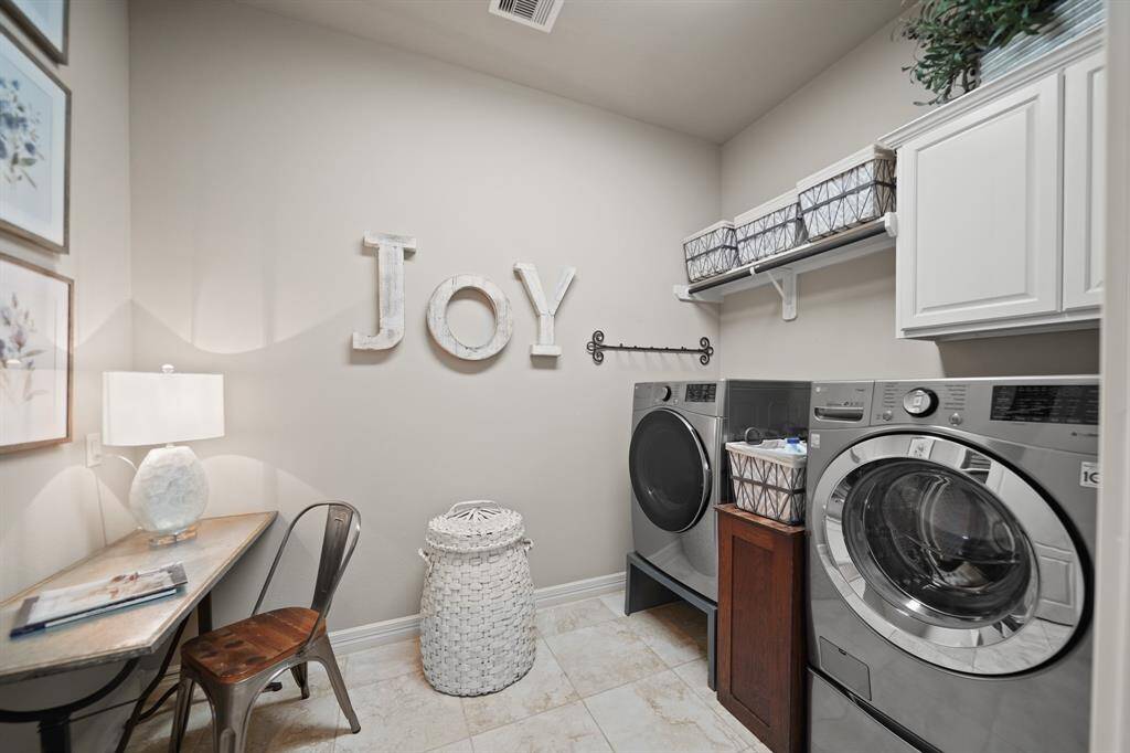 Even the utility room is updated with upgraded cabinetry, tile flooring, built-in shelving and even a custom built in ironing board!