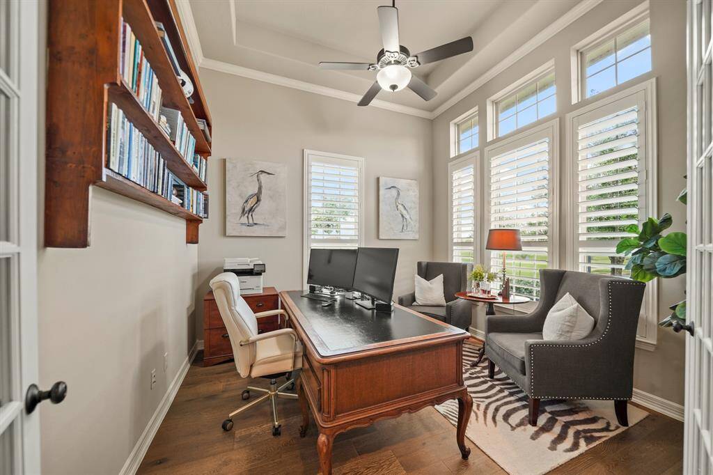 The home office/study just off of the entry enjoys lake views, elegant crown molding and custom wood shutters.