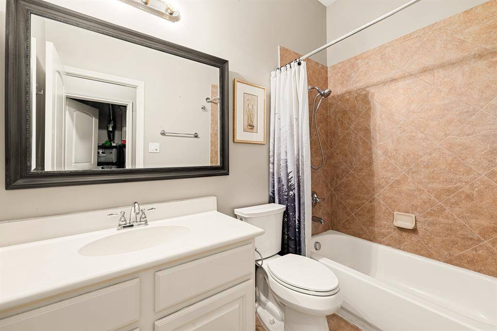 This full Hall bathroom showcases a clean design with modern fixtures and a tiled shower-tub combo.