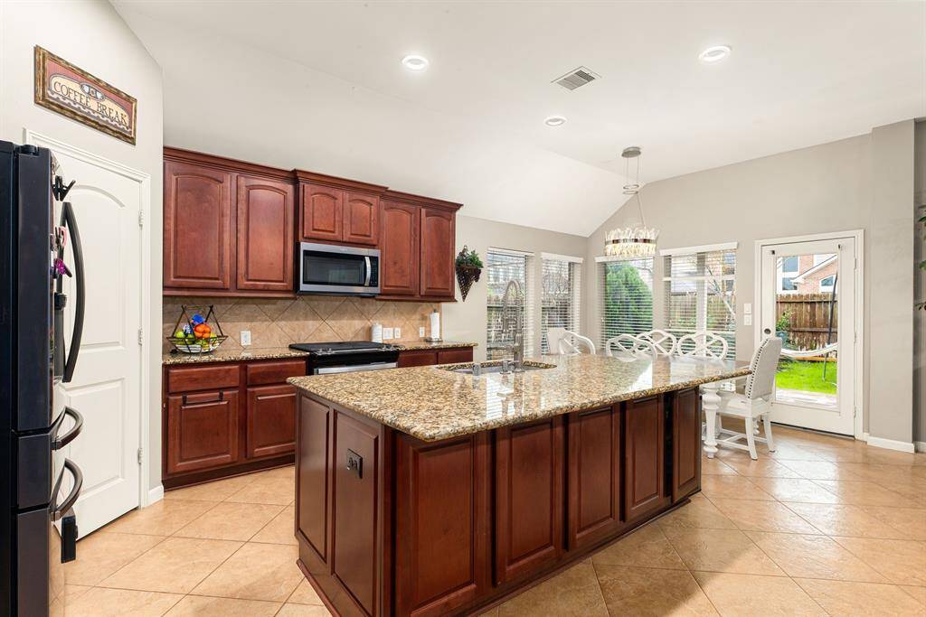 The open-concept kitchen shines with a large island, sleek cabinetry, and backyard views.