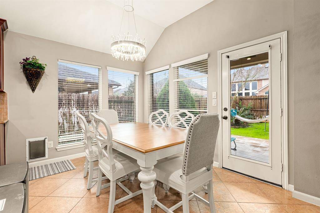 A bright breakfast nook with backyard views provides a cheerful start to every day while boasting a beautiful Artika Chandelier for an elegant look and feel.