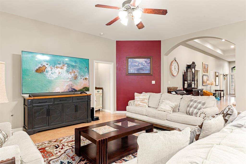 The inviting living room features a bright, open layout with a stylish accent wall and seamless flow into the front of the home, kitchen and dining areas.