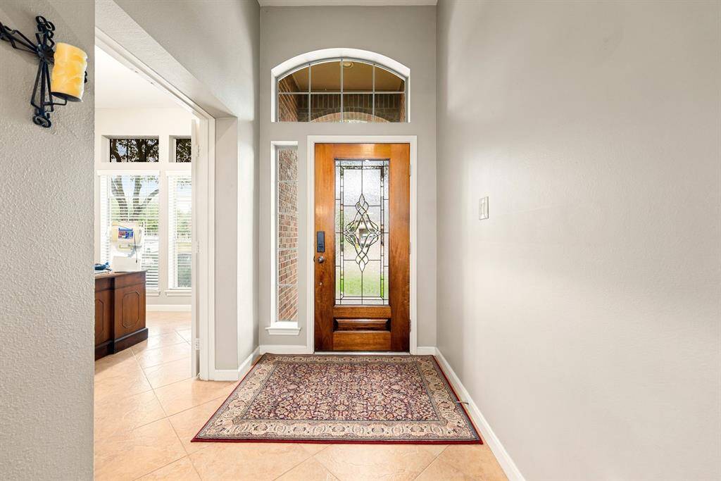 A welcoming entryway showcases elegant architectural details, from the gracefully arched window above the door to the warm tones in the tile. The space feels bright and airy, setting a sophisticated tone for the home.