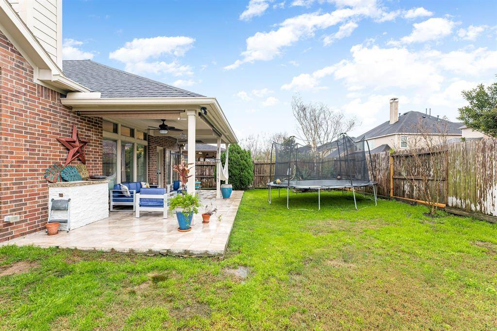 Another view of the backyard highlights the spacious covered patio and mature landscaping.