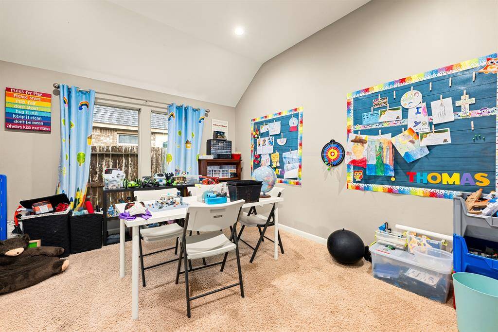 This spacious, versatile room offers a vaulted ceiling and ample space for creative activities or casual gatherings. Natural light brightens the space, highlighting its practical and adaptable layout.