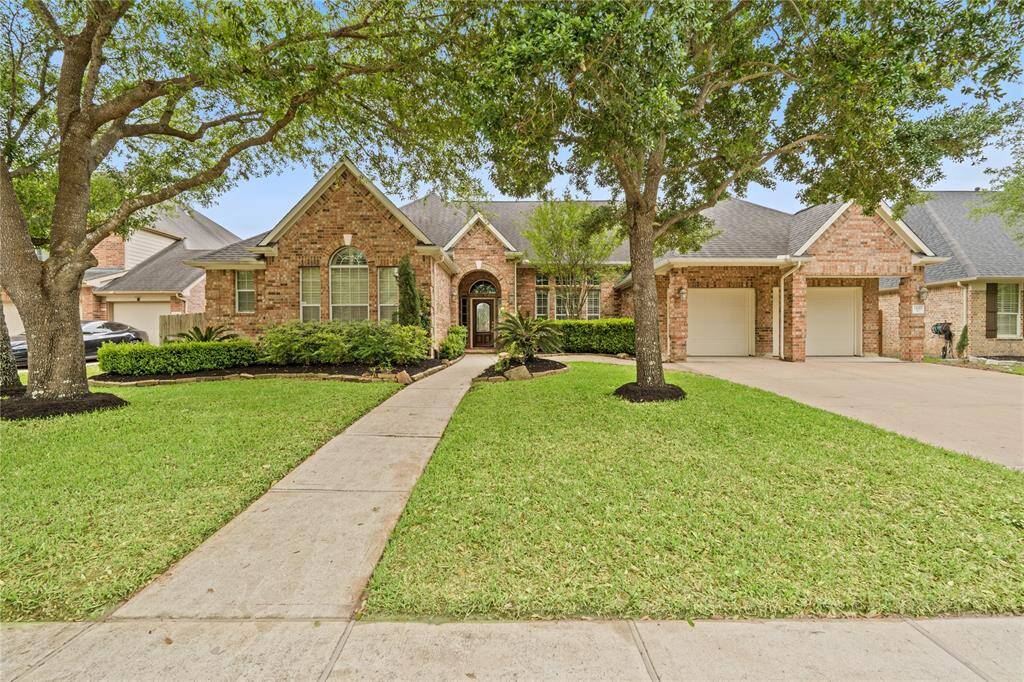 Discover your dream home: a charming brick exterior, lush landscaping, and a welcoming path that leads you inside.