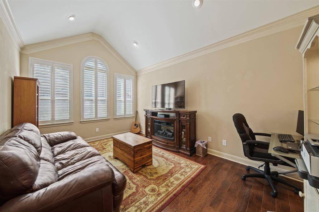 Cozy living space with high ceilings and large windows for natural light. Warm wood flooring enhances the inviting atmosphere.