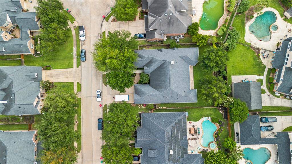 This aerial photo showcases a suburban neighborhood featuring large homes with spacious yards and swimming pools. The area is lush with greenery, and the homes are situated along a quiet, curved cul-de-sac street, offering an attractive, family-friendly environment.