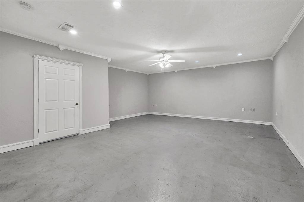This spacious room features neutral walls, recessed lighting, and a ceiling fan, offering a versatile area perfect for customization. Ideal for a family room or entertainment space.
