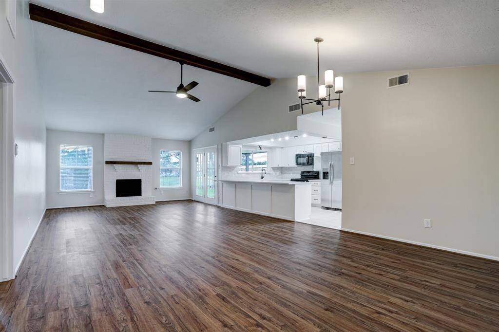 Upon entering, you're greeted with a vaulted ceiling and a stained mantel and beam. Additionally, the durable darker laminate wood and constrasting light fixtures give this home a modern upgrade, while maintaining traditional feel.