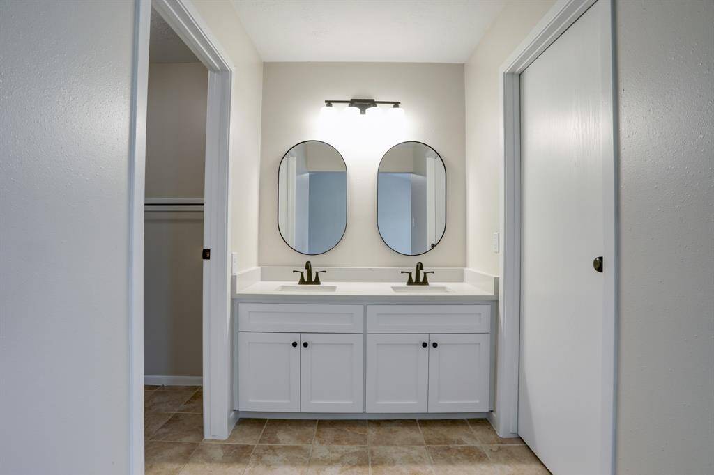 Off the primary bedroom is the en-suite bathroom vanity with double sinks.  Vanity, light fixture, faucets, countertops, and mirrors were installed 2/24.