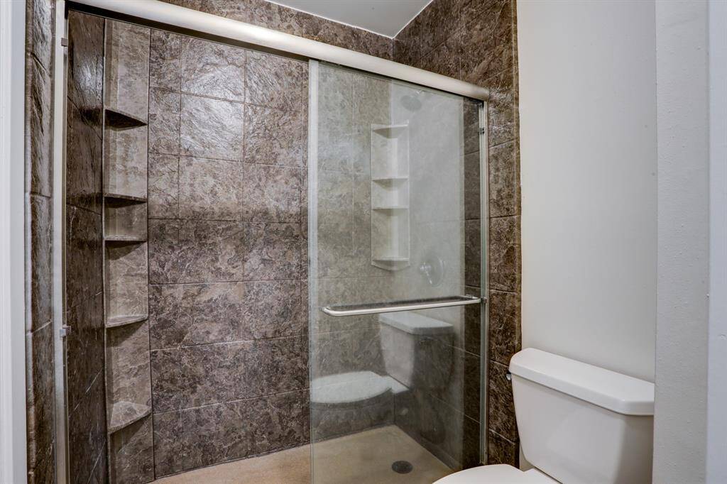 To the left of the primary bathroom vanity, you will find the shower with sliding glass door and linen closet.