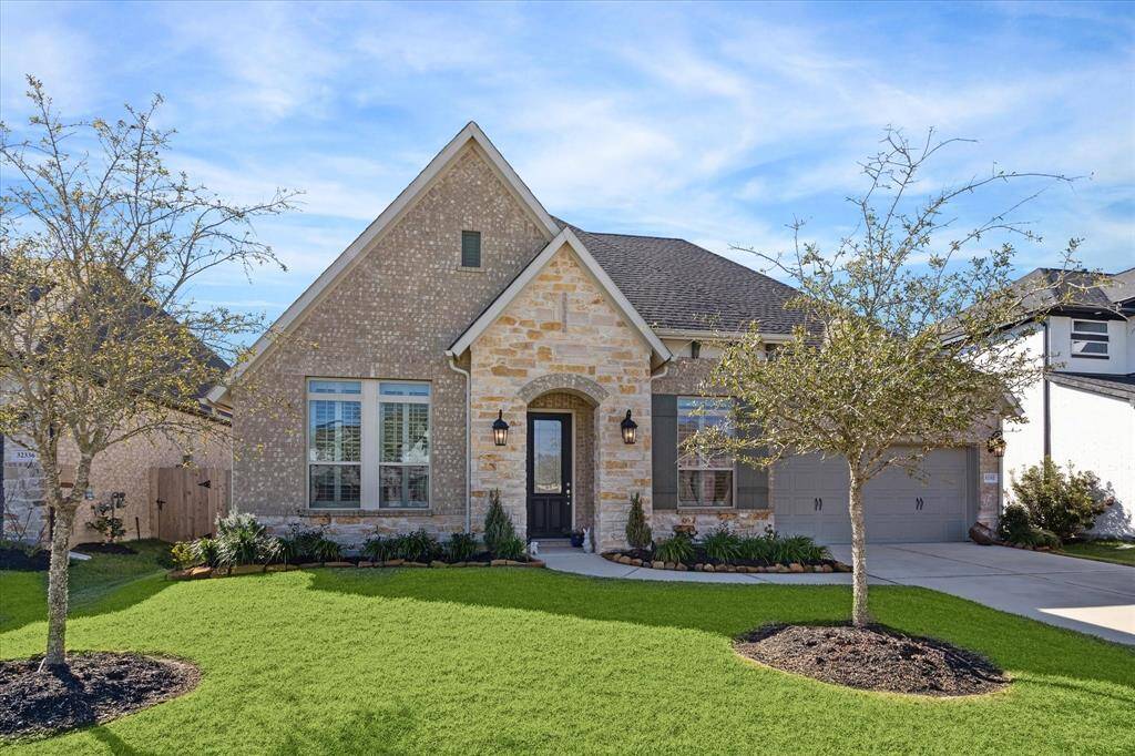 This exceptionally charming one-story David Weekley home features curb appeal with a mix of brick and stone, a beautifully manicured lawn, and landscaping in the sought-after Meadows at Imperial Oaks.