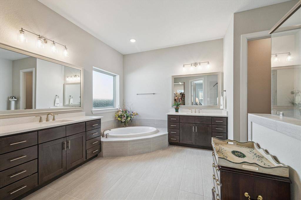 The primary bathroom features dual vanities with Blanco Maple quartz countertops, Kent Moore Groveland Grey Wolf cabinets, a soaking tub, and a separate shower, creating a true retreat and elevating this space into a relaxing sanctuary.