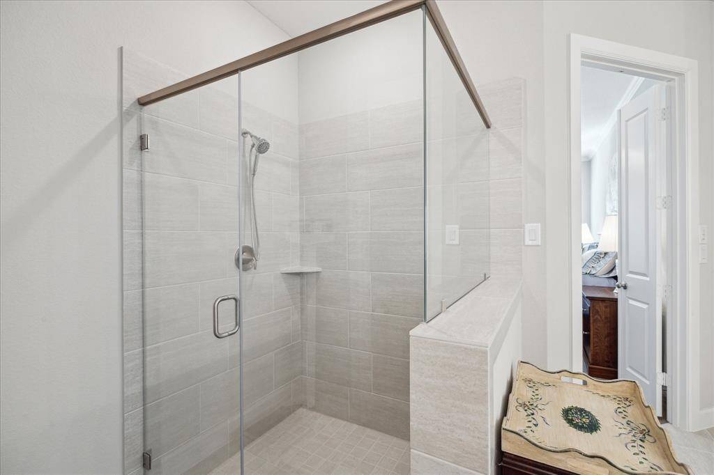 The owner’s ensuite bathroom features ITSG Contessa Pewter 12x24 tile for flooring and in the spacious walk-in shower, paired with sleek Moen nickel plumbing fixtures creating a luxurious, spa-like experience.