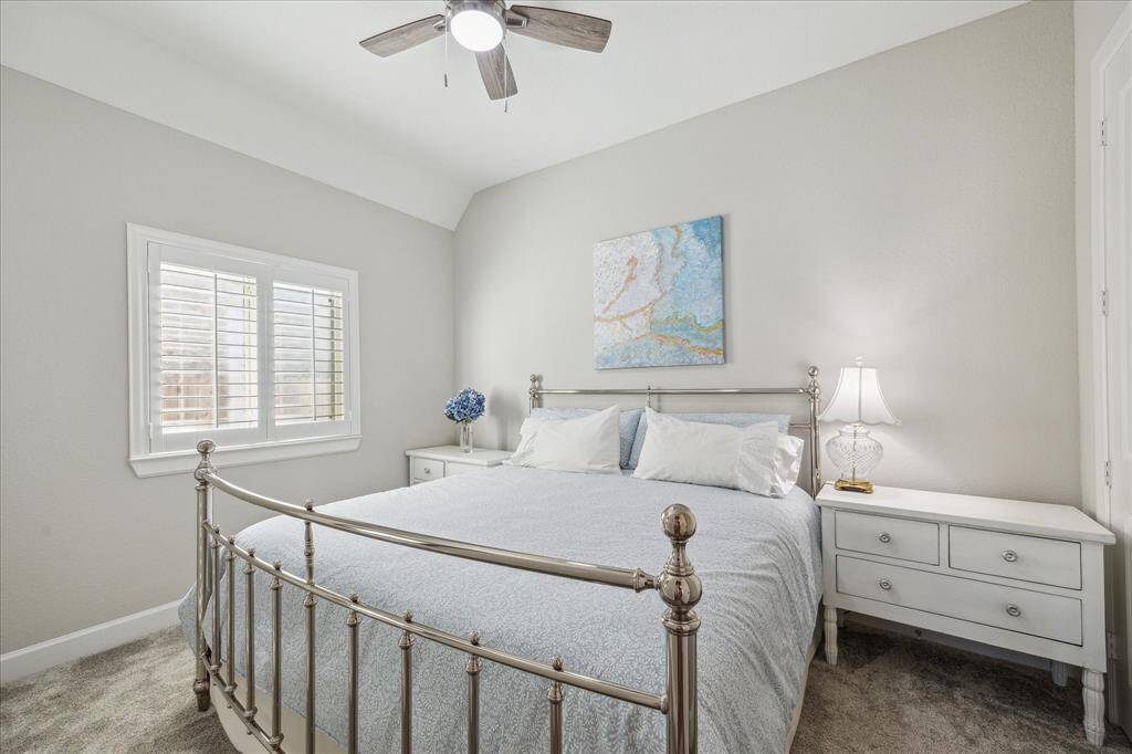 Another spacious secondary bedroom featuring plush carpeting and walls painted in Sherwin-Williams Agreeable Gray, maintaining the home's bright and inviting aesthetic, offering ample natural light and a serene atmosphere.