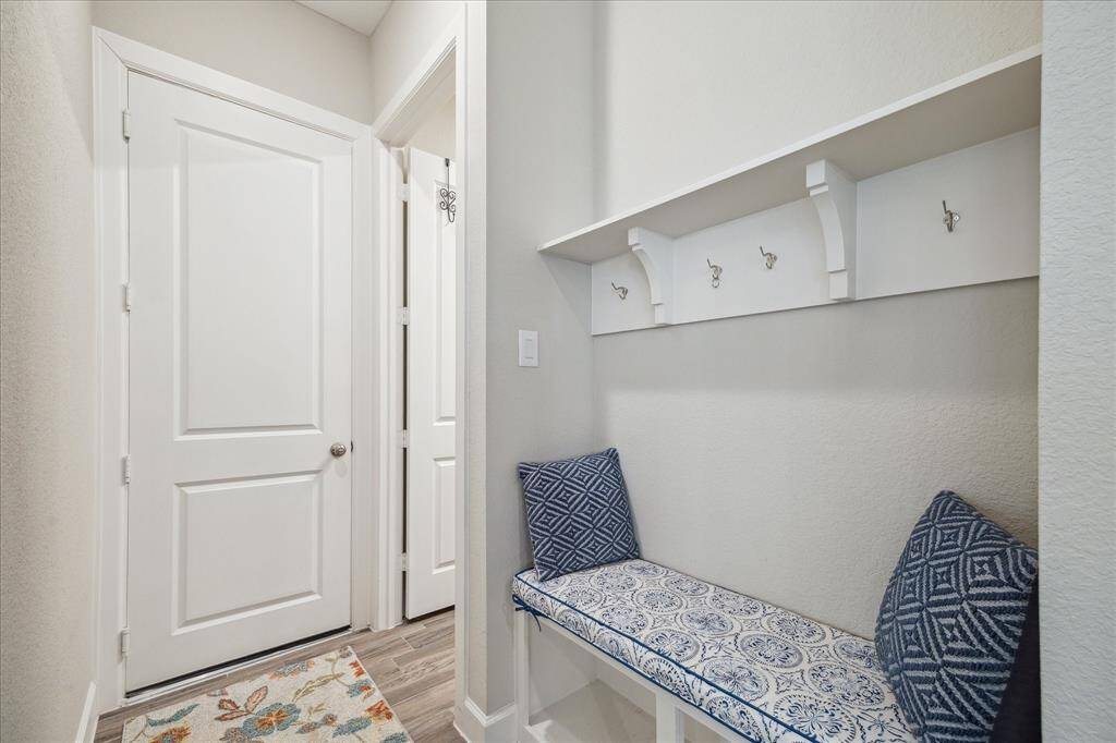 The conveniently located backpack rack, situated between the garage, utility room, and kitchen, features a built-in bench with hooks and storage, offering a practical and inviting space to organize coats, bags, and shoes.