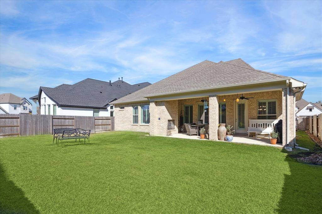 The private backyard with plenty of open space, perfect for enjoying sunny days or hosting outdoor activities, and a view of the covered patio for seamless indoor-outdoor living.  Ideal for relaxation and entertaining.