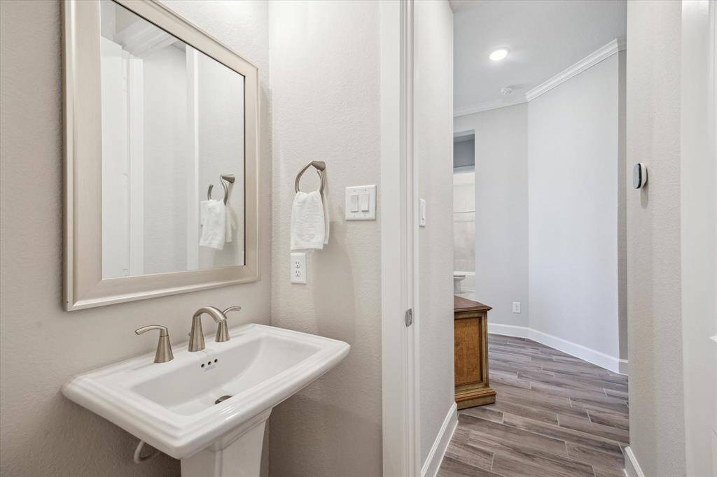 This charming powder room features a pedestal sink, framed mirror, and neutral tones, offering a convenient and stylish space for guests.