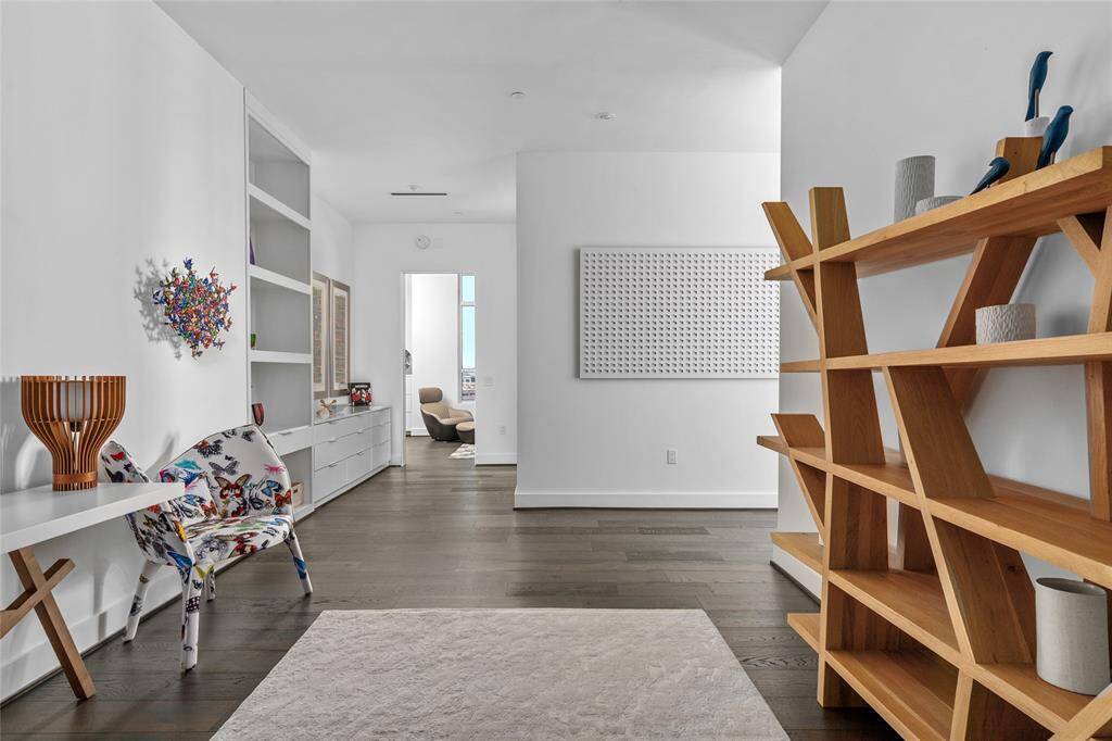 Featuring built-in shelves and storage, as well as large gallery walls perfect for showcasing art, the foyer creates a sophisticated transition space that separates the living and dining areas from the primary and secondary bedrooms, blending functionality with refined design.