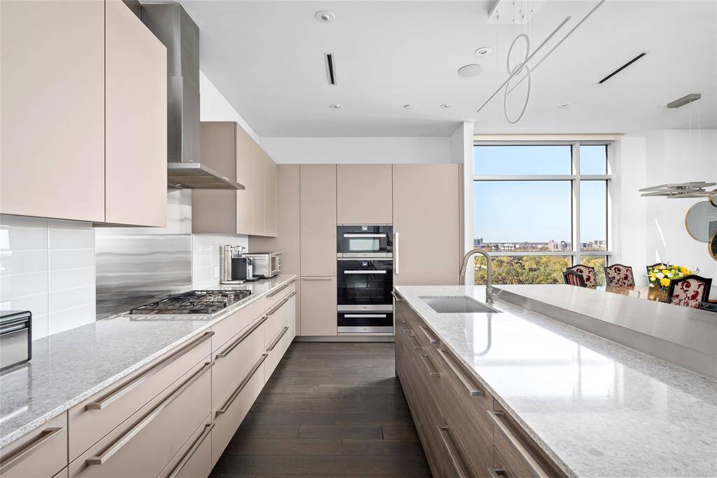 The kitchen is equipped with a premium Miele appliance package, including a 5-burner gas range, oven, microwave, warming drawer, and two beverage drawers. Hansgrohe plumbing fixtures, soft-close pot and pan drawers, and undercabinet lighting add to the functionality and elegant design.
