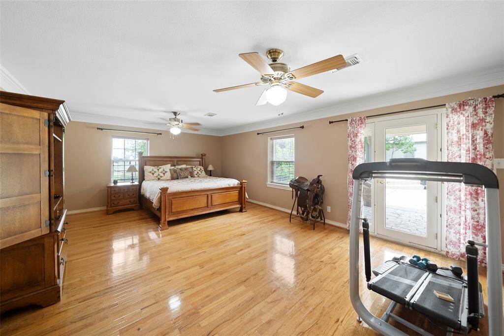 The spacious primary suite offers gleaming hardwood floors, multiple windows for great natural light, and direct access to the backyard patio.